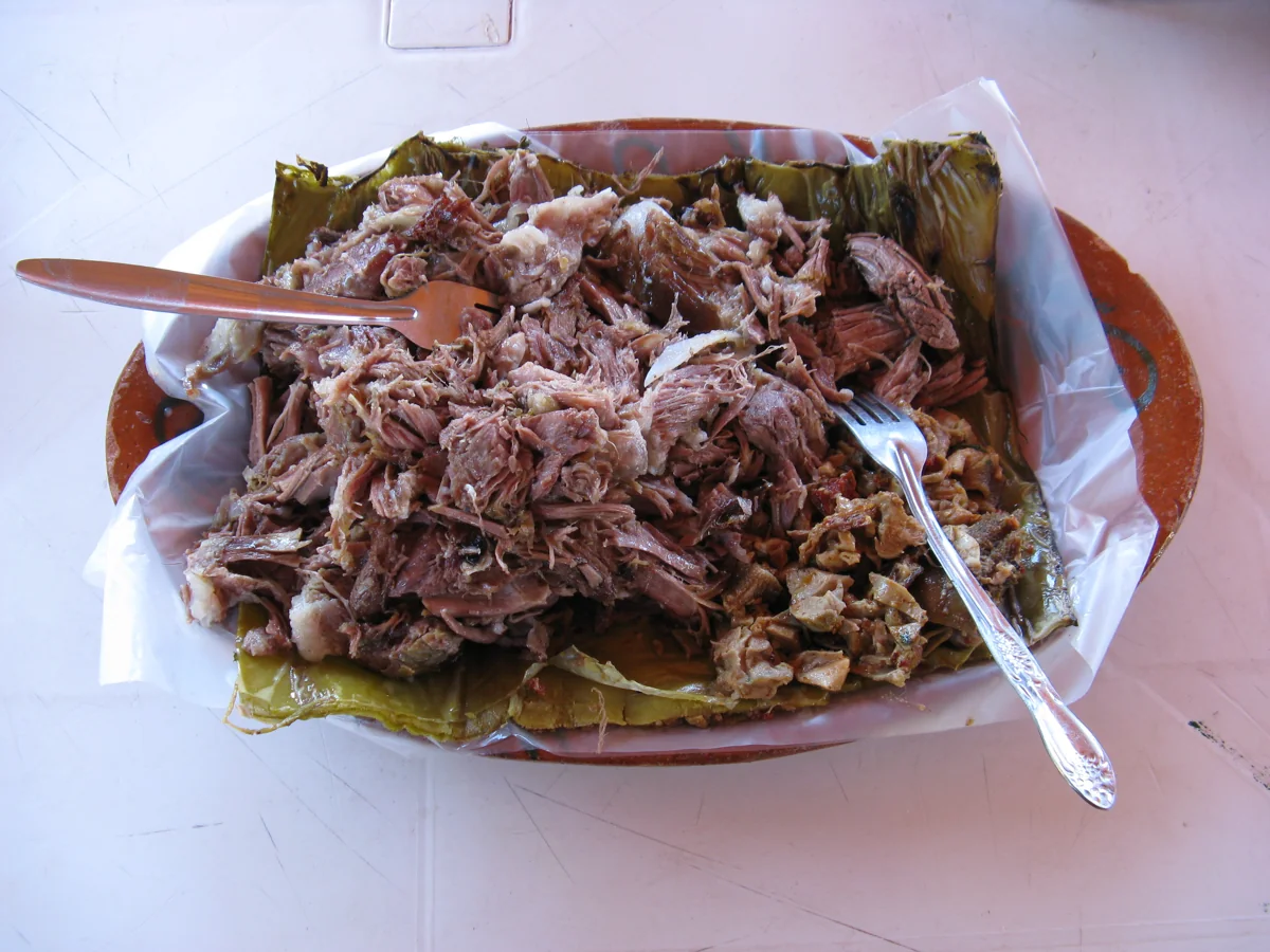 Barbacoa de borrego: Carnero cocido lentamente en horno de tierra, envuelto en pencas de maguey hasta quedar suave y jugoso.