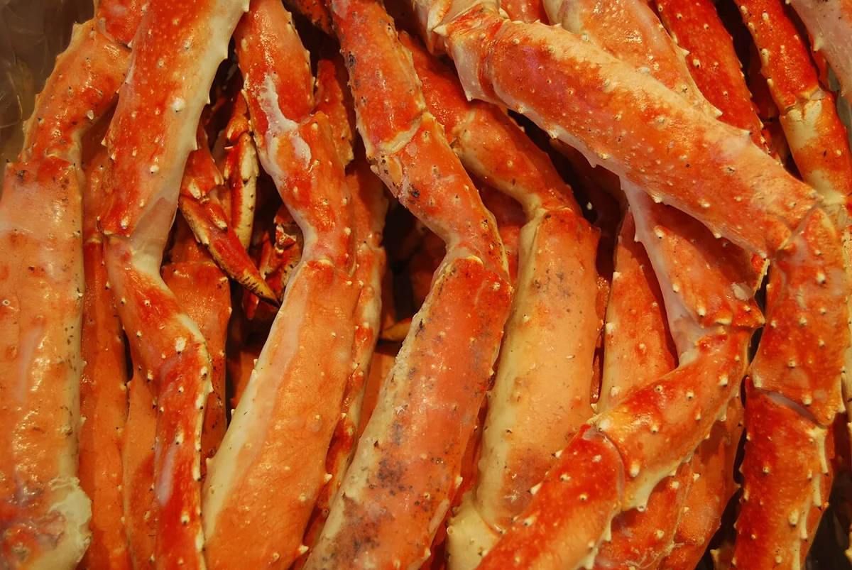 Cangrejo real de Alaska: Patas de cangrejo real de Alaska cocidas al vapor y servidas con mantequilla derretida y limón, un manjar del mar de Bering.