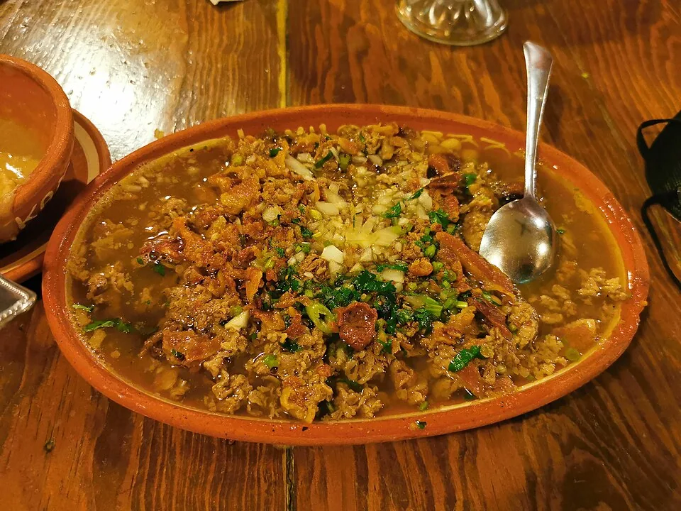 Carne en su jugo: Bistec finamente picado cocido en su caldo con frijoles bayos, tocino y salsa verde.