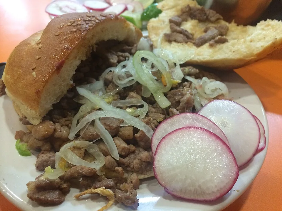 Cemita poblana: Torta poblana con pan de ajonjolí, milanesa, quesillo y pápalo.