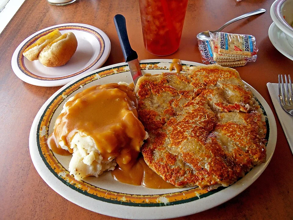 Chicken fried steak: Bistec empanizado y frito como pollo, servido con salsa blanca de pimienta (white gravy).