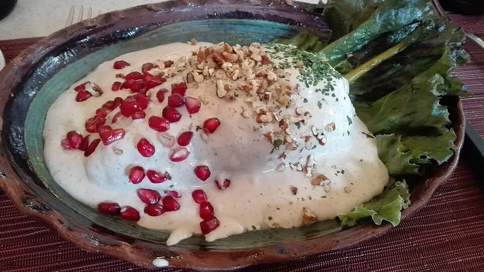 Chiles en nogada: Chile poblano relleno de picadillo, bañado en nogada de nuez y granada.