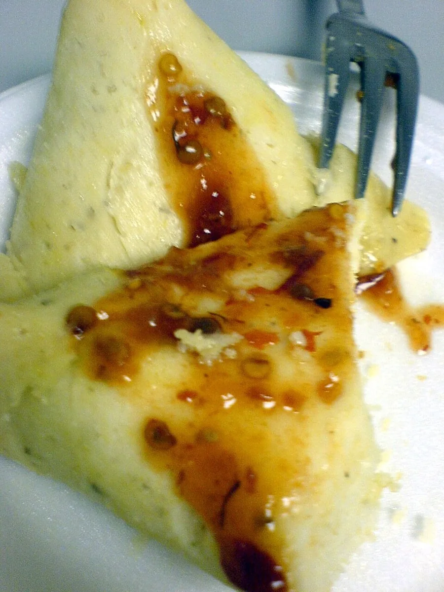 Corundas: Tamal triangular de masa envuelto en hoja de milpa, servido con crema, salsa y queso.