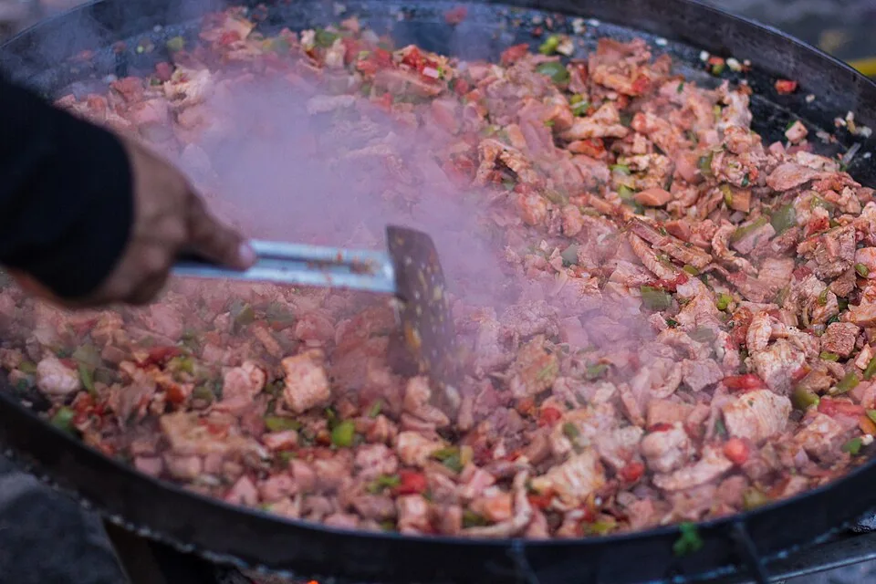 Discada norteña: Mezcla de carnes y embutidos cocinada sobre un disco de arado al aire libre, festín de reunión norteño.