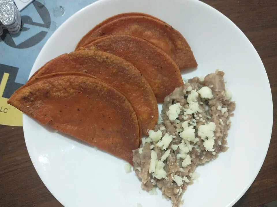 Enchiladas potosinas: Tortillas de masa amasada con chile ancho, rellenas de queso y cebolla, doradas en comal.