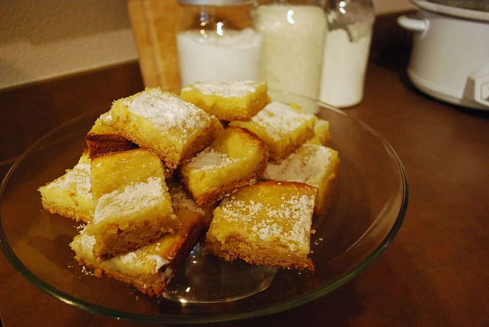 Gooey butter cake de San Luis: Pastel plano y denso con base de masa dulce y una capa superior pegajosa de mantequilla y azúcar, cubierta de azúcar glas.