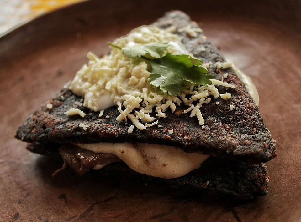 Itacates de Tepoztlán: Antojito triangular de masa de maíz con queso, dorado en comal y relleno de guisos al gusto.