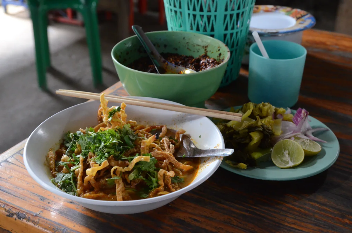 Khao Soi: Curry cremoso del norte con fideos, pollo y fideos fritos encima.