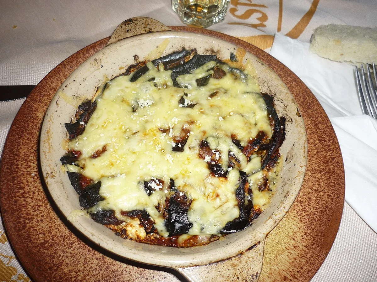 Moussaka: Capas de berenjena y cordero con tomate, cubiertas de bechamel y queso gratinado.