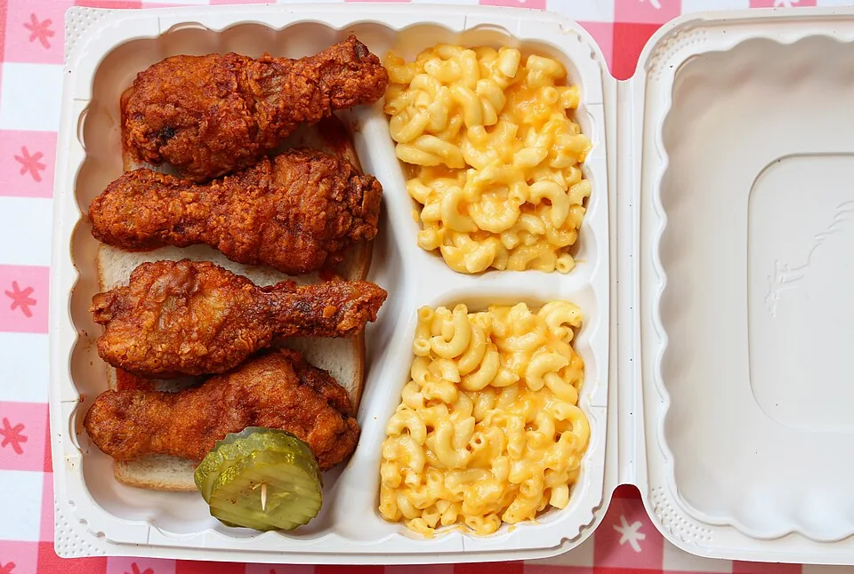 Nashville hot chicken: Pollo frito bañado en una pasta ardiente de cayena y manteca caliente, servido sobre pan blanco con pepinillos.