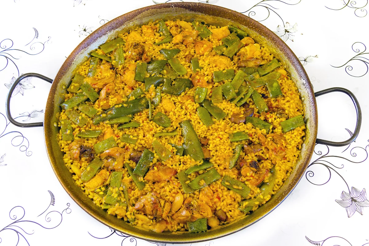 Paella valenciana: Arroz seco valenciano con pollo, conejo, judías verdes, garrofó y azafrán.