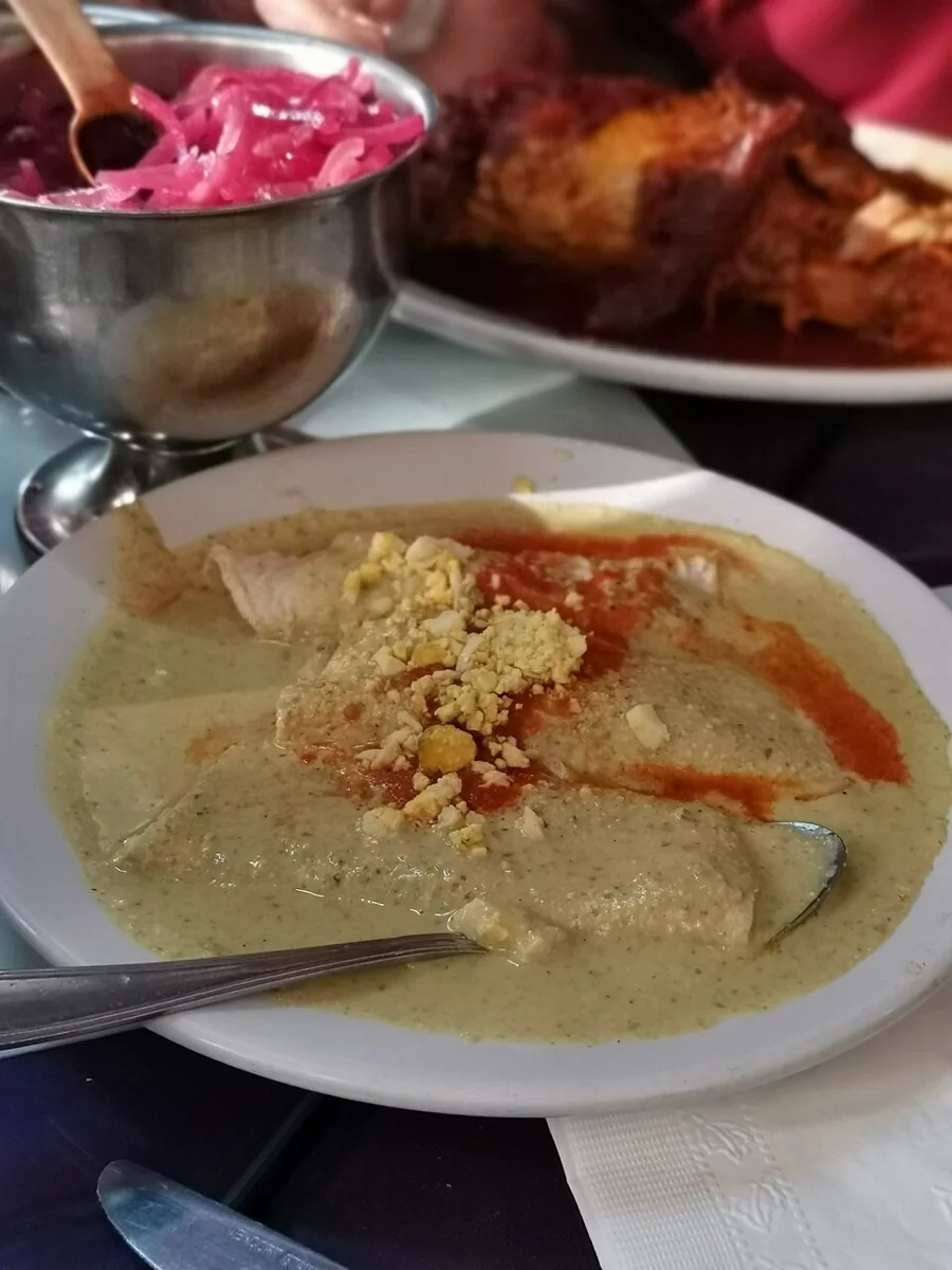 Papadzules: Tacos de huevo cocido bañados en salsa de pepita de calabaza y aceite de semilla, con salsa de jitomate.