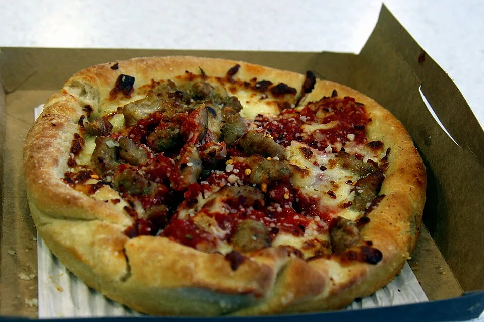 Pizza deep-dish de Chicago: Pizza de molde alto y bordes gruesos con el queso abajo, relleno generoso y salsa de tomate encima, marca registrada de Chicago.