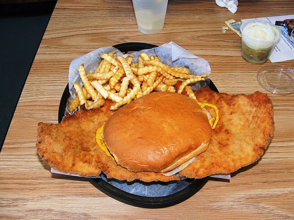 Sándwich de lomo de cerdo empanizado: Filete de lomo de cerdo aplanado, empanizado y frito, tan grande que desborda por mucho el pan que lo sostiene.