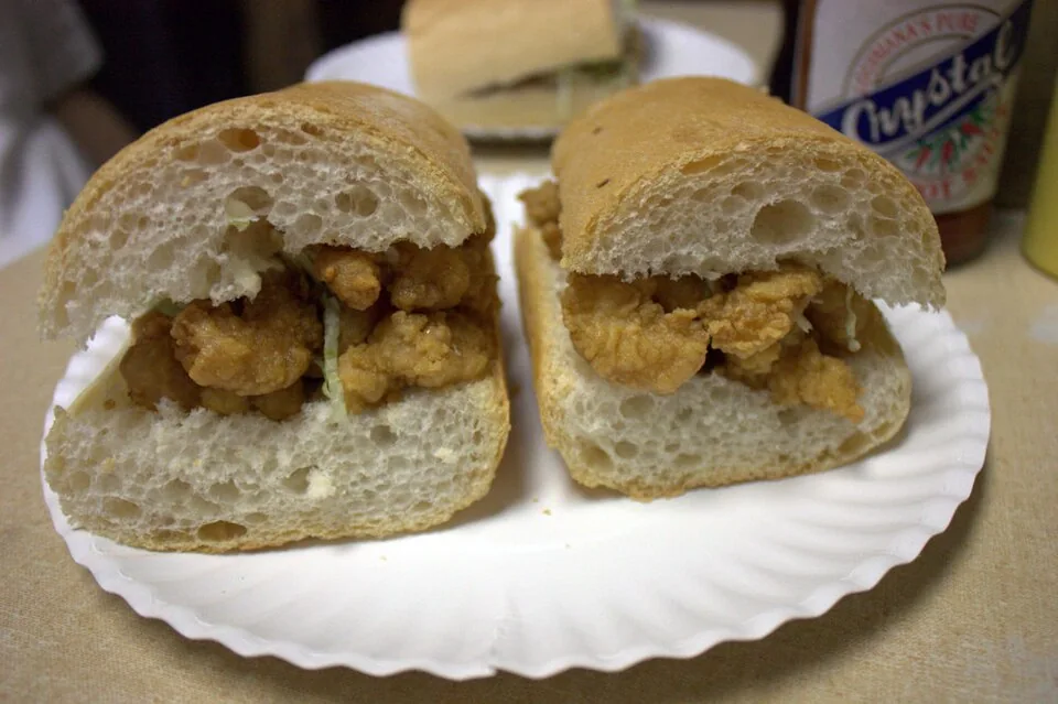 Po'boy de camarón: Baguette crujiente de Nueva Orleans rellena de camarones empanizados y fritos, con lechuga, tomate y mayonesa.