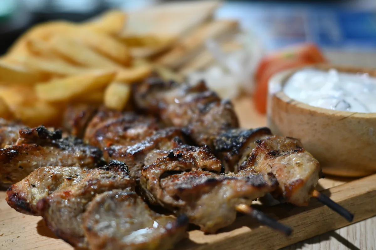 Souvlaki: Brochetas griegas de pollo marinado con limón, ajo y orégano, servidas en pita con tzatziki.