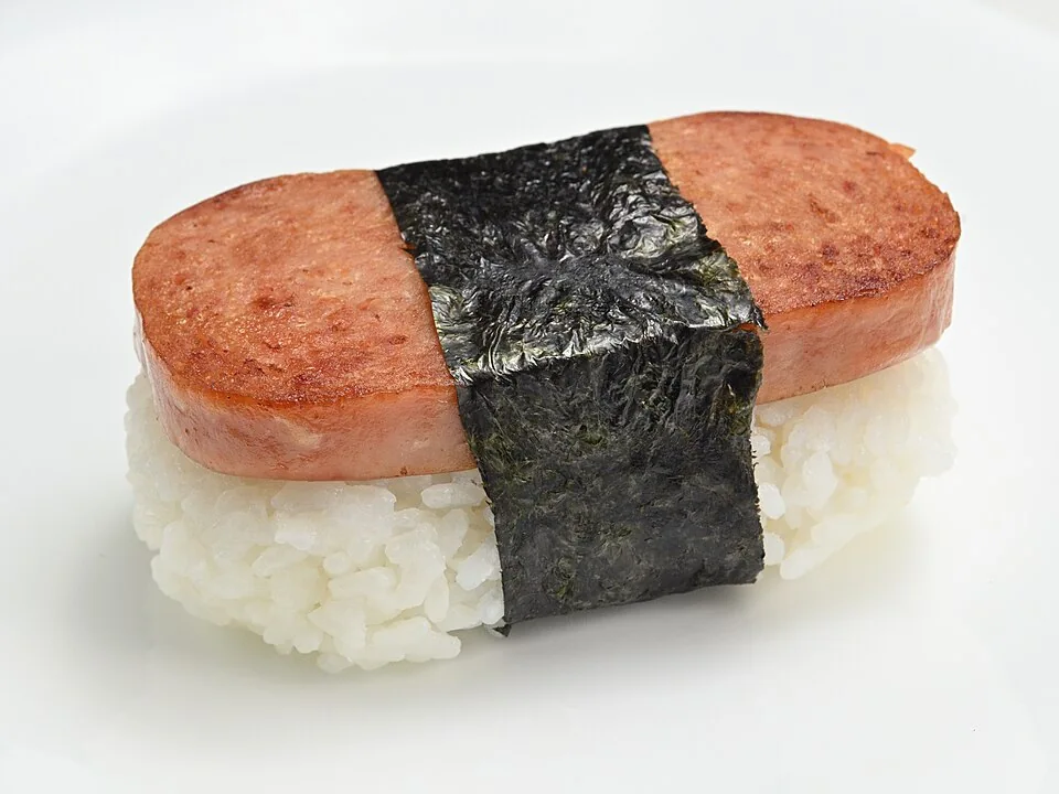 Spam musubi: Bocado de arroz prensado con una rebanada de Spam glaseado, envuelto en una tira de alga nori, muy popular como snack en Hawái.