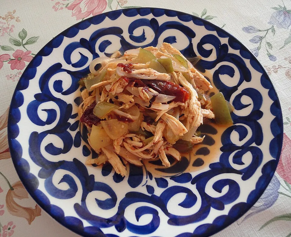 Tinga poblana: Pollo deshebrado guisado con jitomate, cebolla y chipotle, servido sobre tostadas.