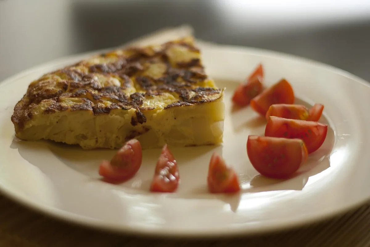 Tortilla española de papa: Tortilla de papa y cebolla, dorada por fuera y completamente cuajada en el centro.